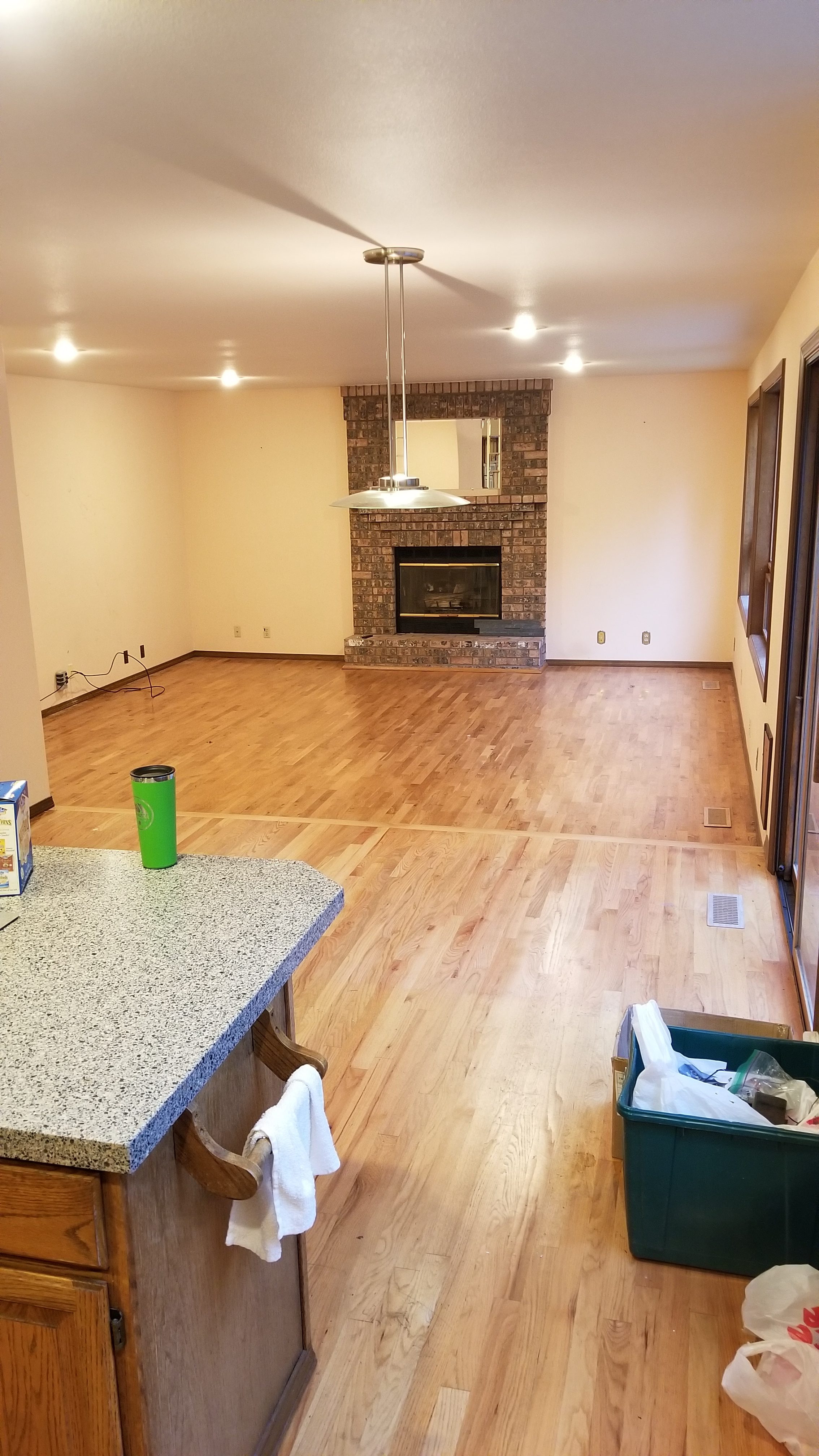 Open-plan kitchen and living area before remodel showing the sunken living room step-down, oak cabinetry, and dated finishes