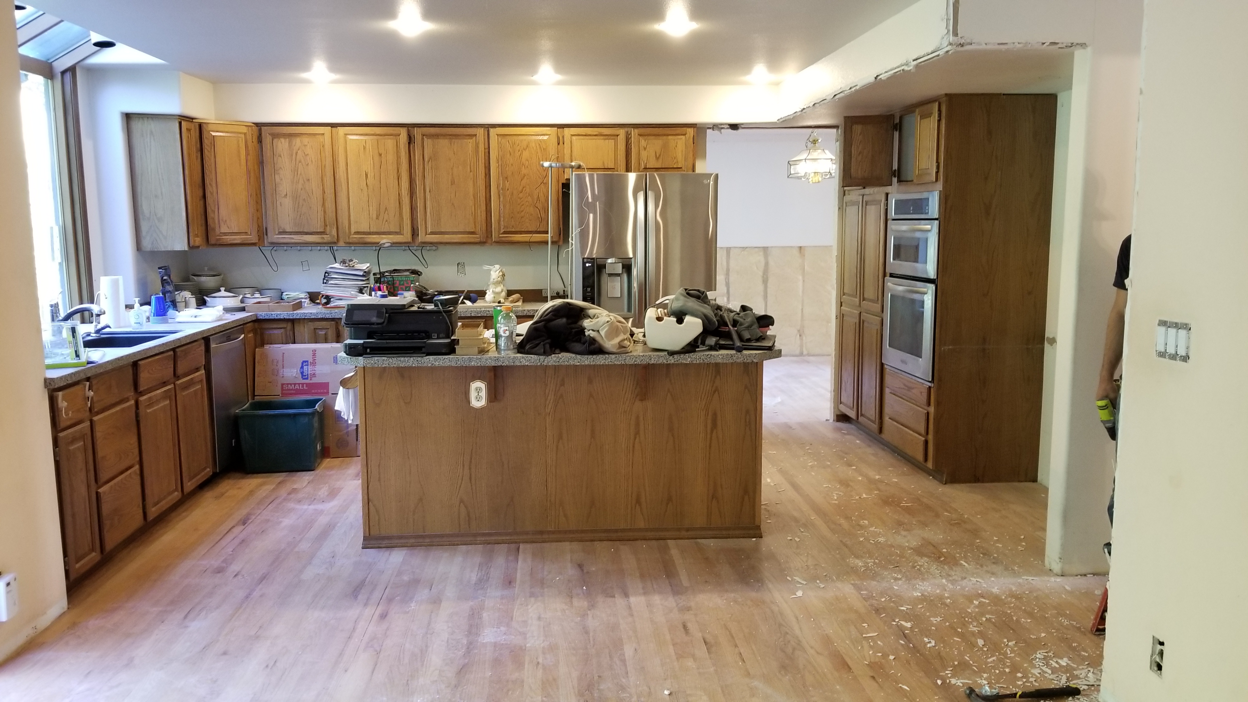 Clyde Hill home before the remodel, with the original kitchen and main floor mid-demolition, showing dated honey-oak cabinetry and exposed subfloor