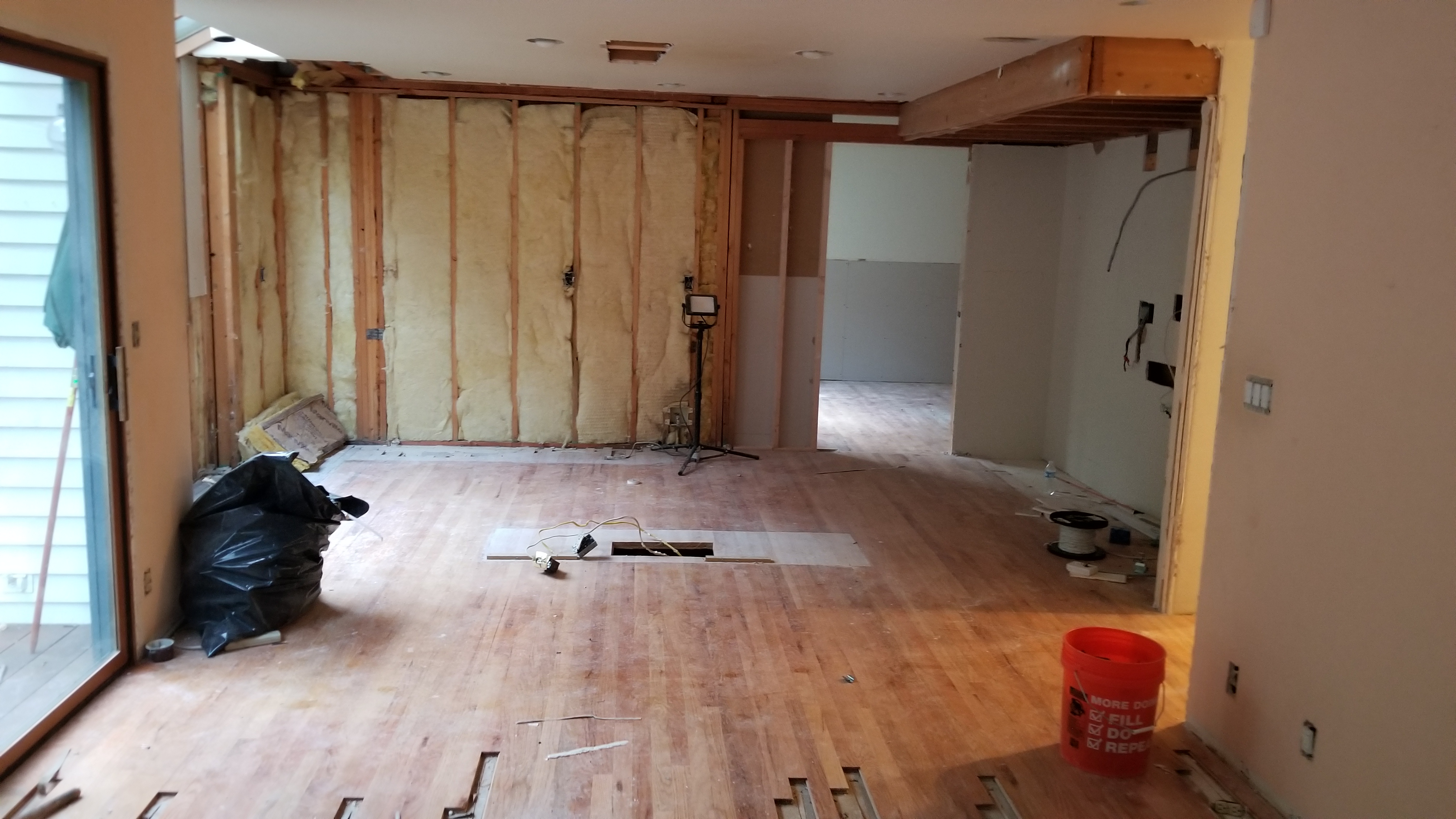 Main living space gutted to studs with exposed wiring and open wall cavities during the whole-home remodel