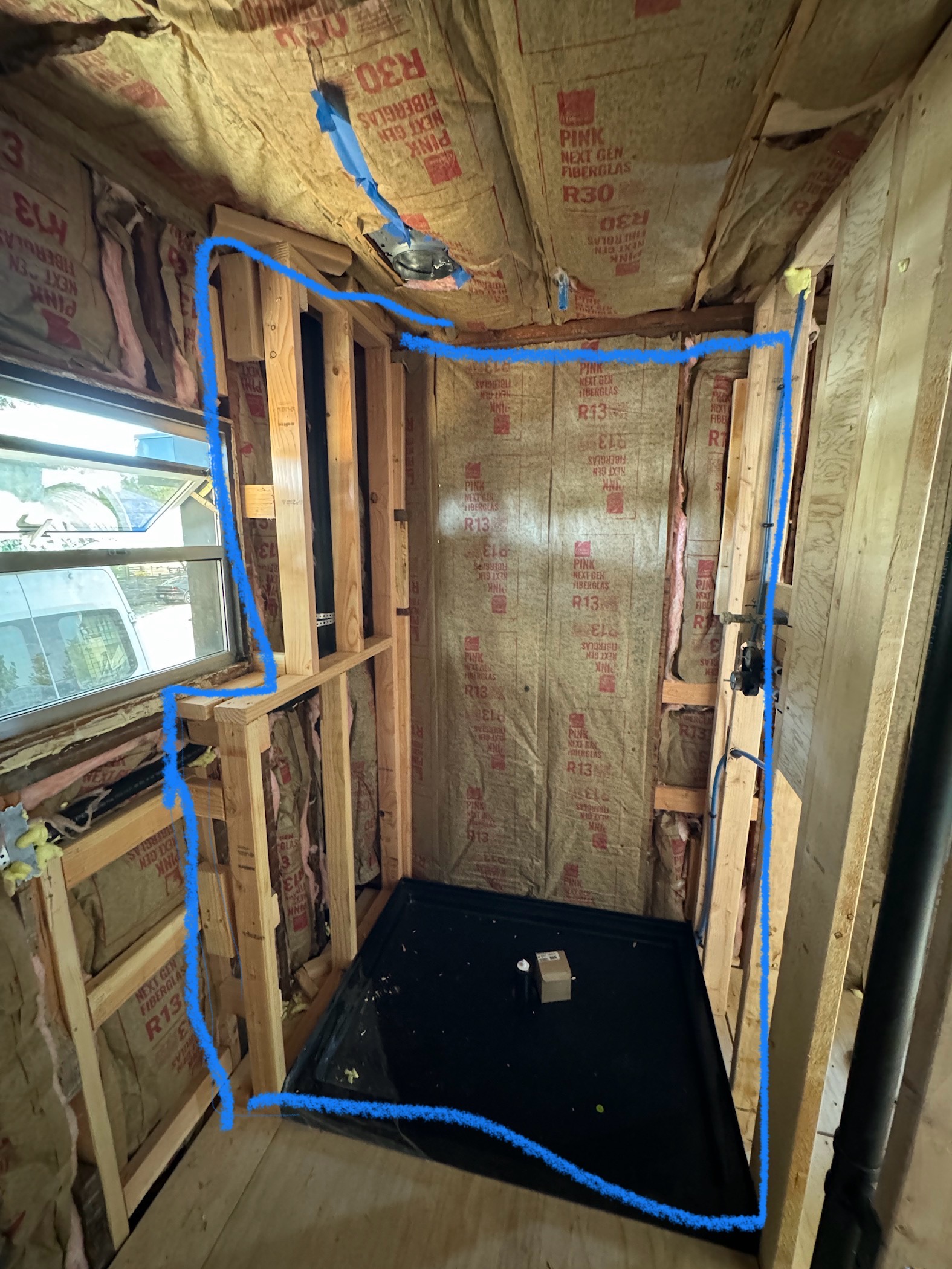Insulated bathroom walls with the shower pan set and the shower layout marked out before tile