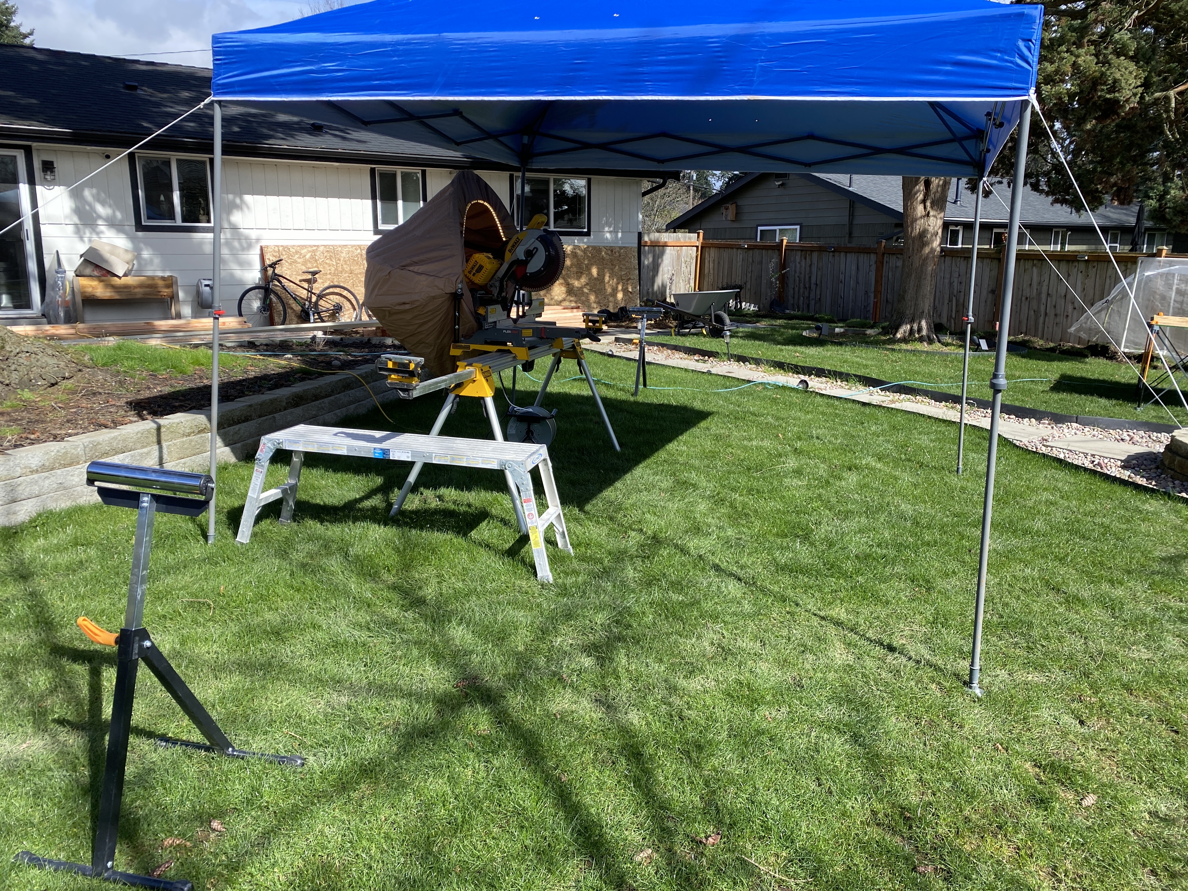 Bothell backyard staged for construction with canopy, miter saw station and protected lawn and hardscape