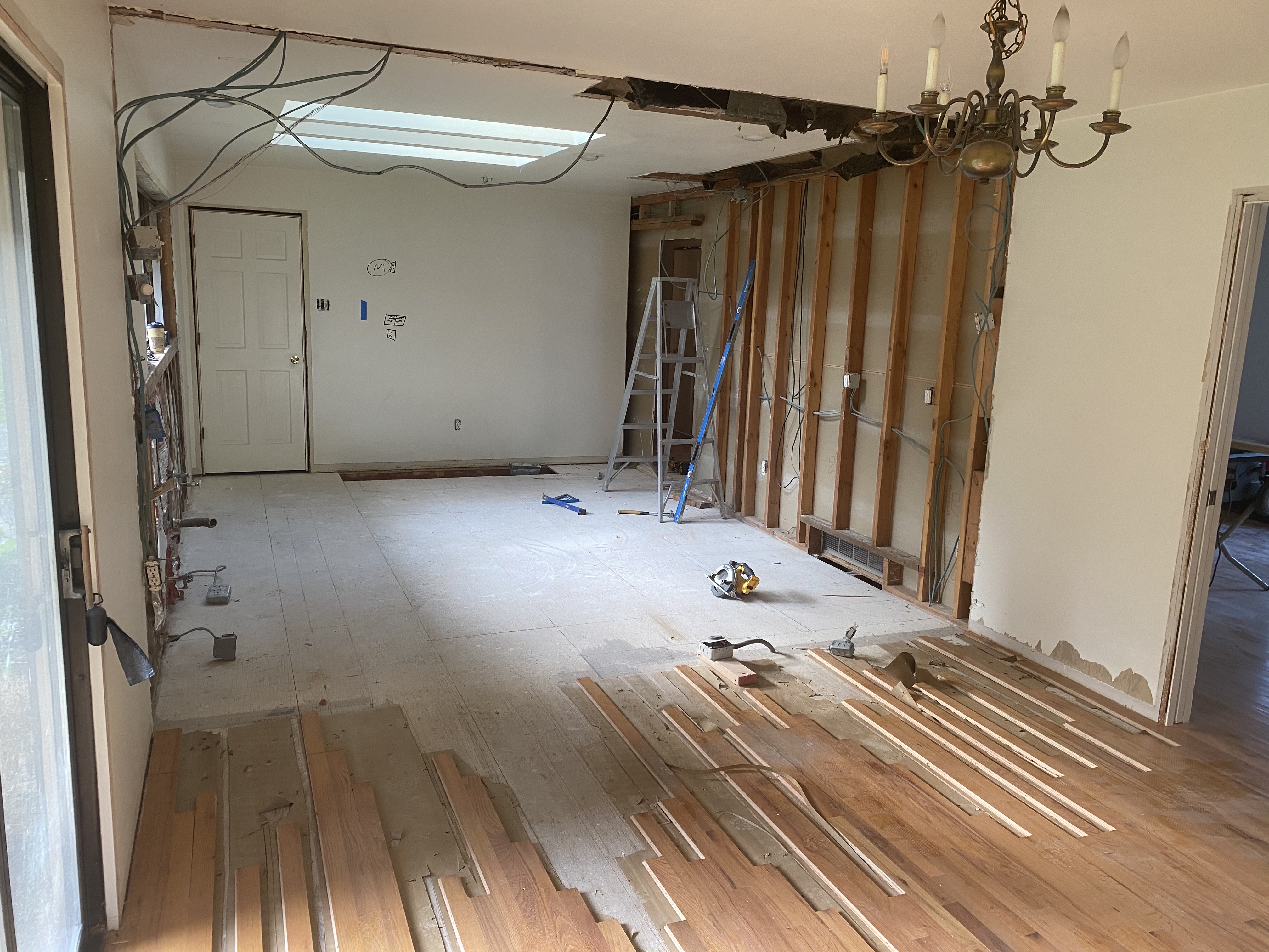 Before photo of the Issaquah home during demolition, with the living room gutted to the studs, hardwood flooring removed, and a load-bearing wall exposed