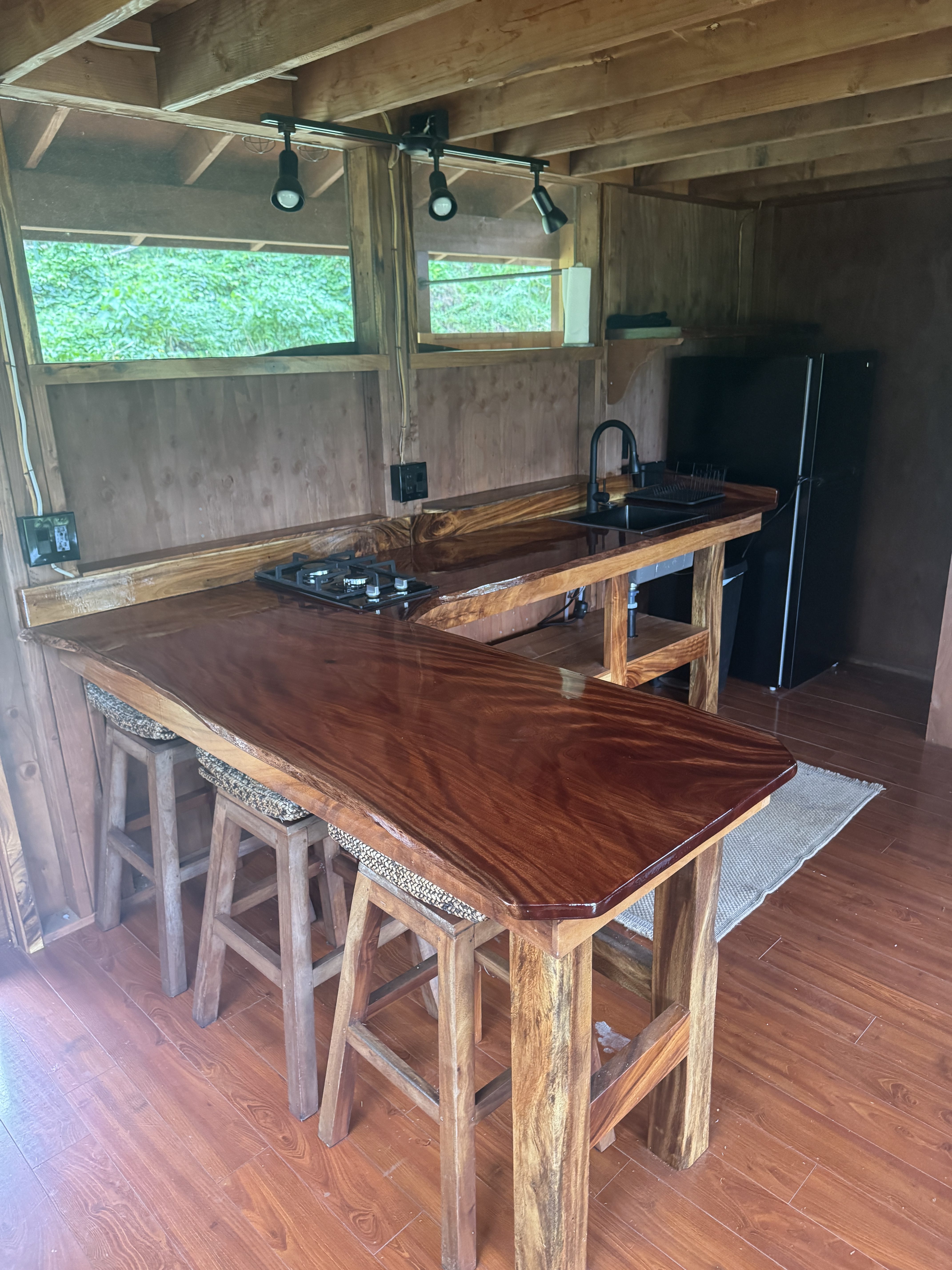 An L-shaped live-edge hardwood breakfast bar with wooden stools in a cabin kitchen