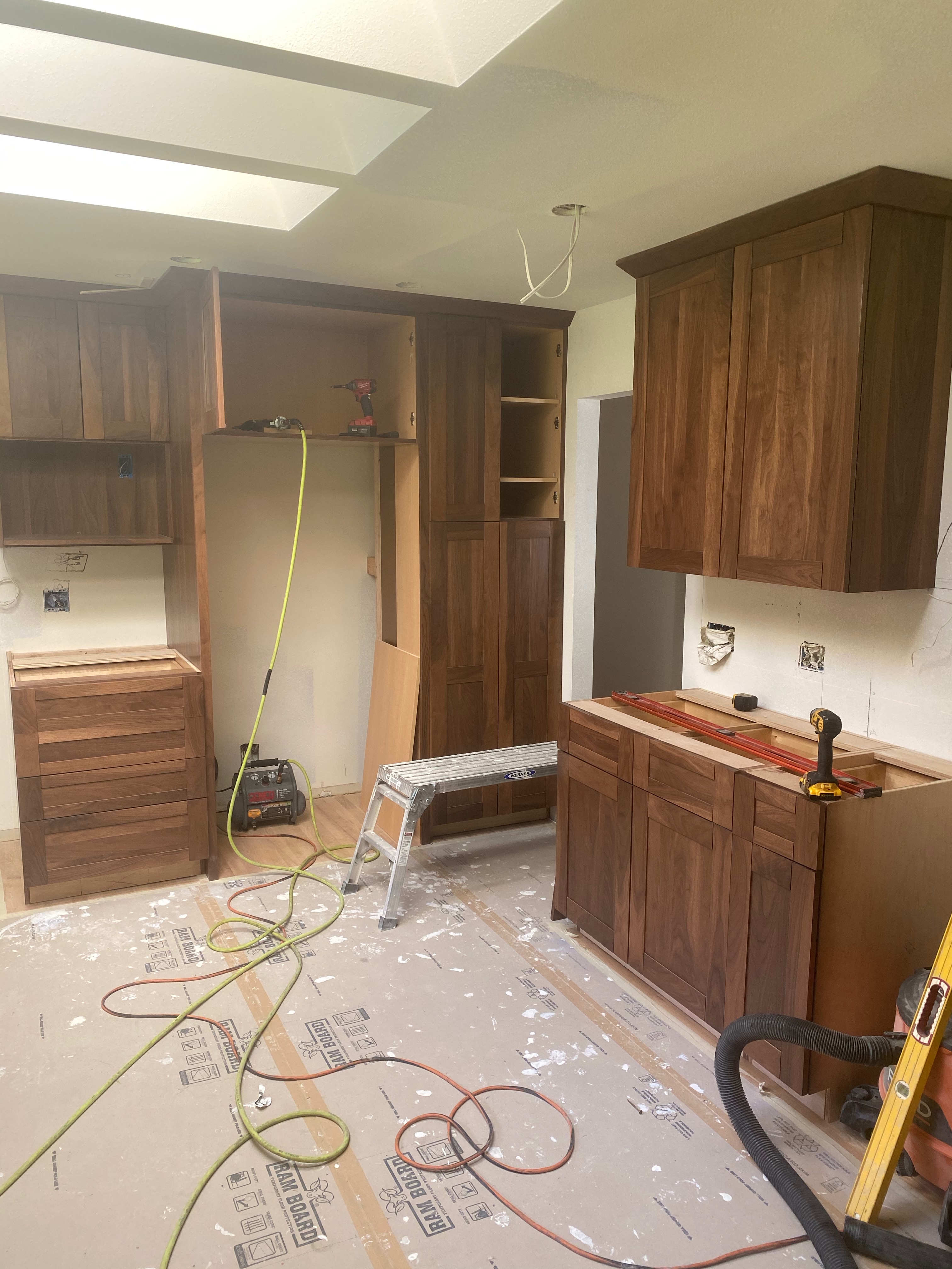 Custom walnut Omega cabinetry being installed during the Issaquah kitchen remodel with floor protection down