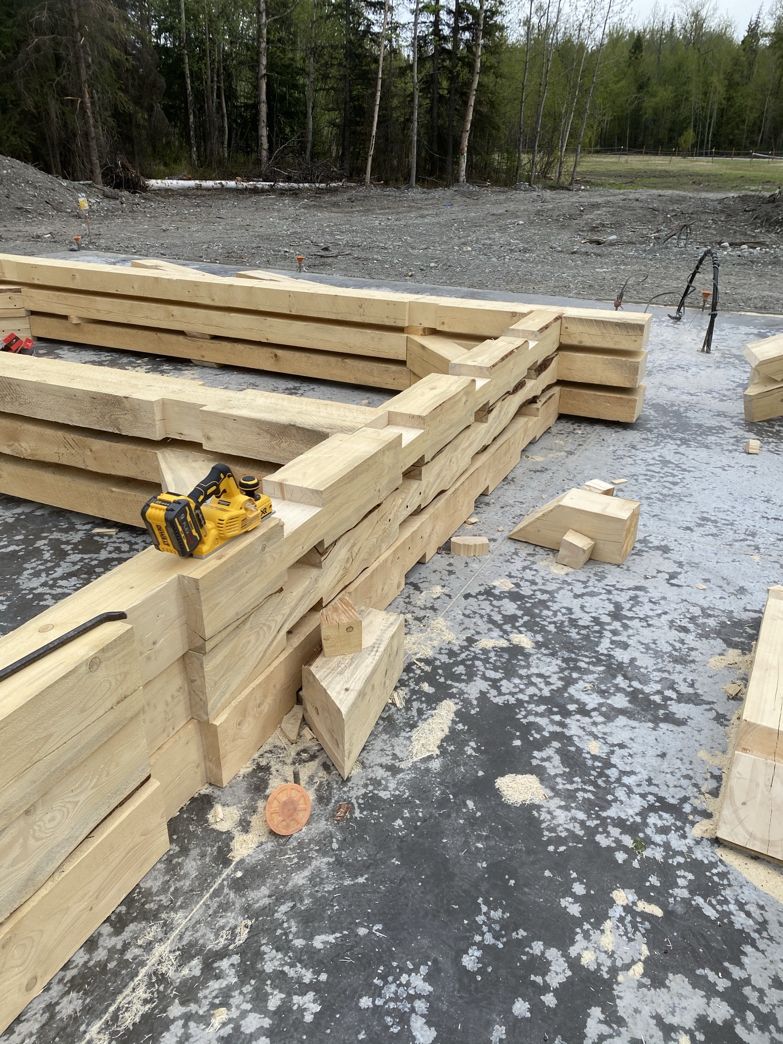 Second-story studio loft with fresh wood decking and large windows staged for installation, forest view beyond