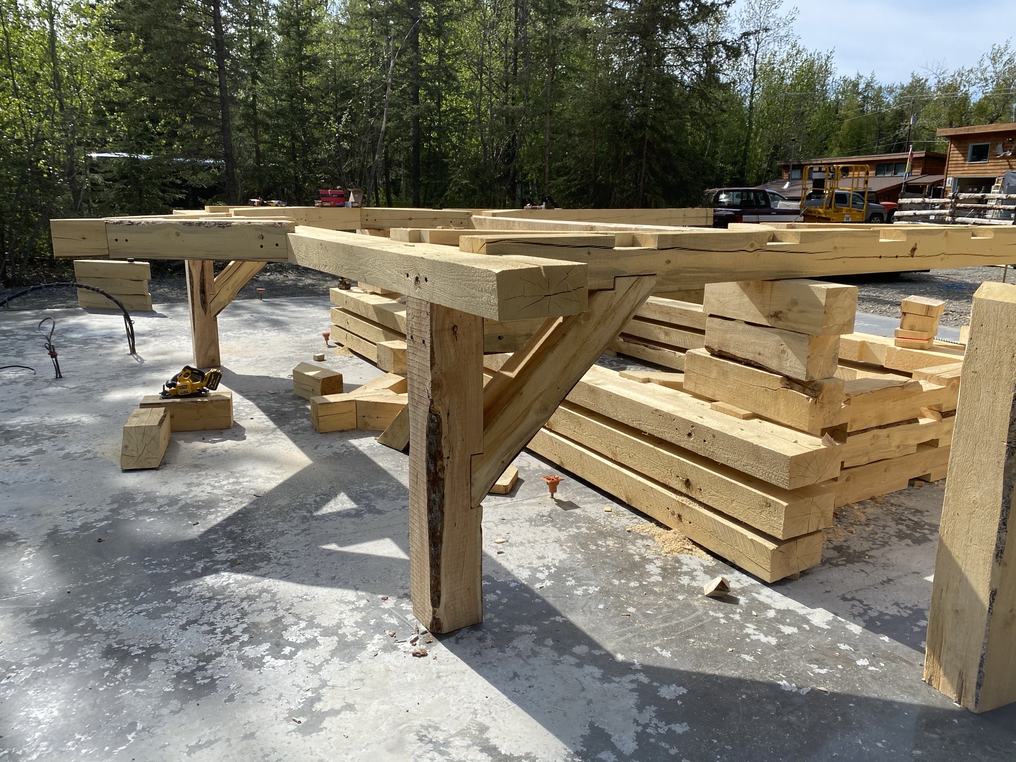 Timber frame bents and curved corbel braces laid out on the concrete slab during assembly in Snohomish, Washington