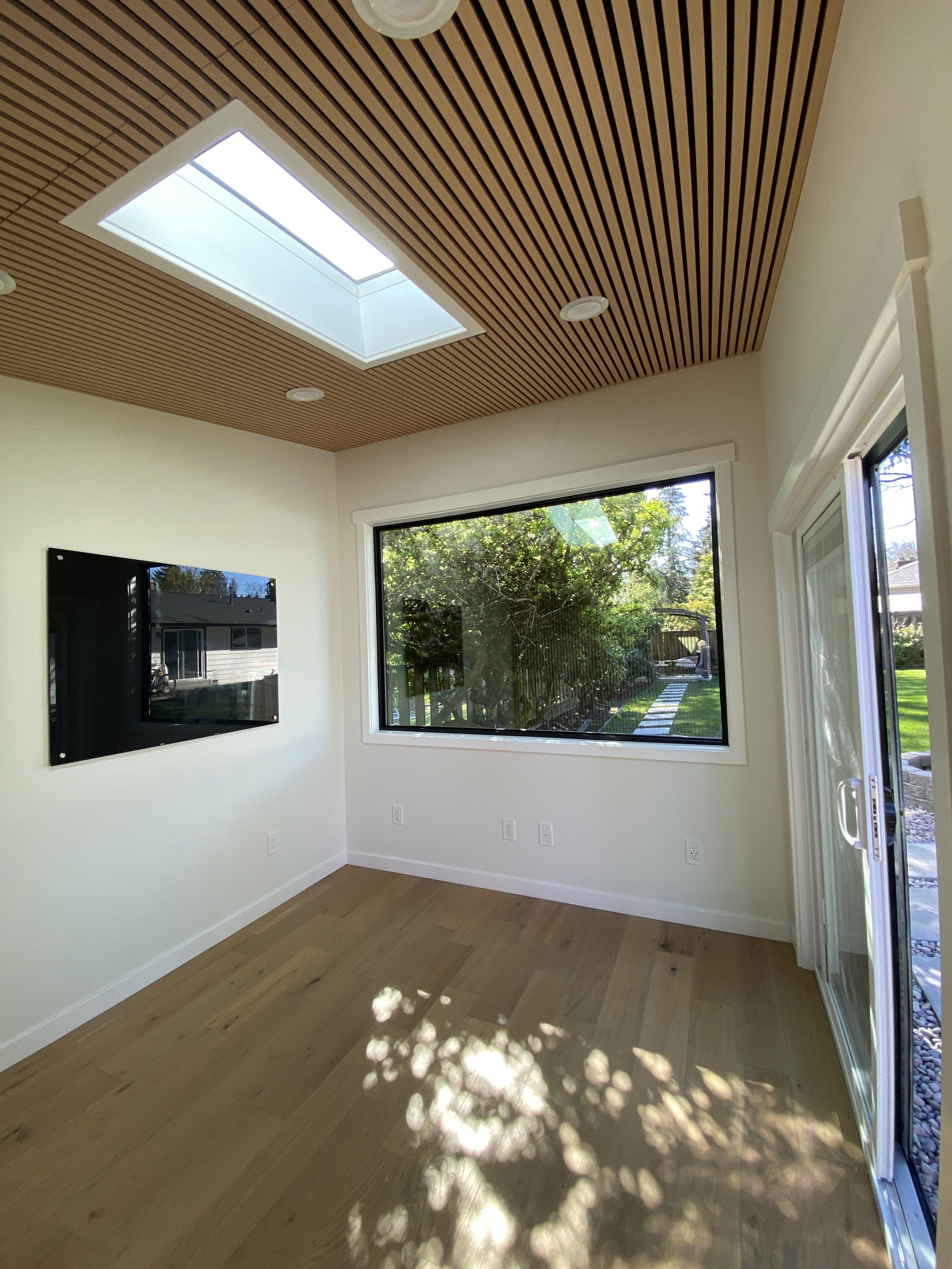Studio office interior showing skylight, acoustic slat ceiling, recessed LED lights and hardwood flooring