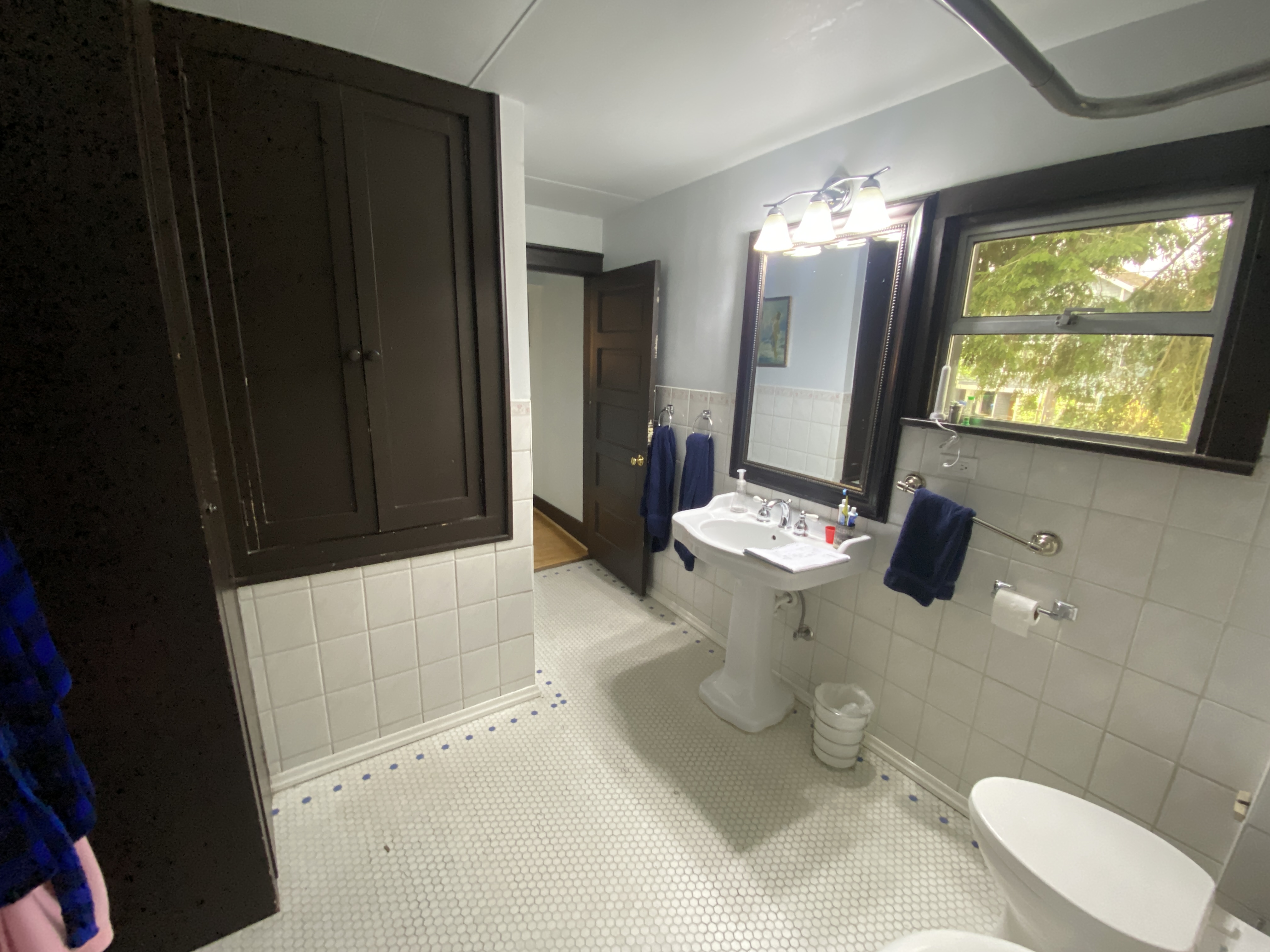 Before: original bathroom with a dark built-in cabinet and aging tile in a Bellevue home
