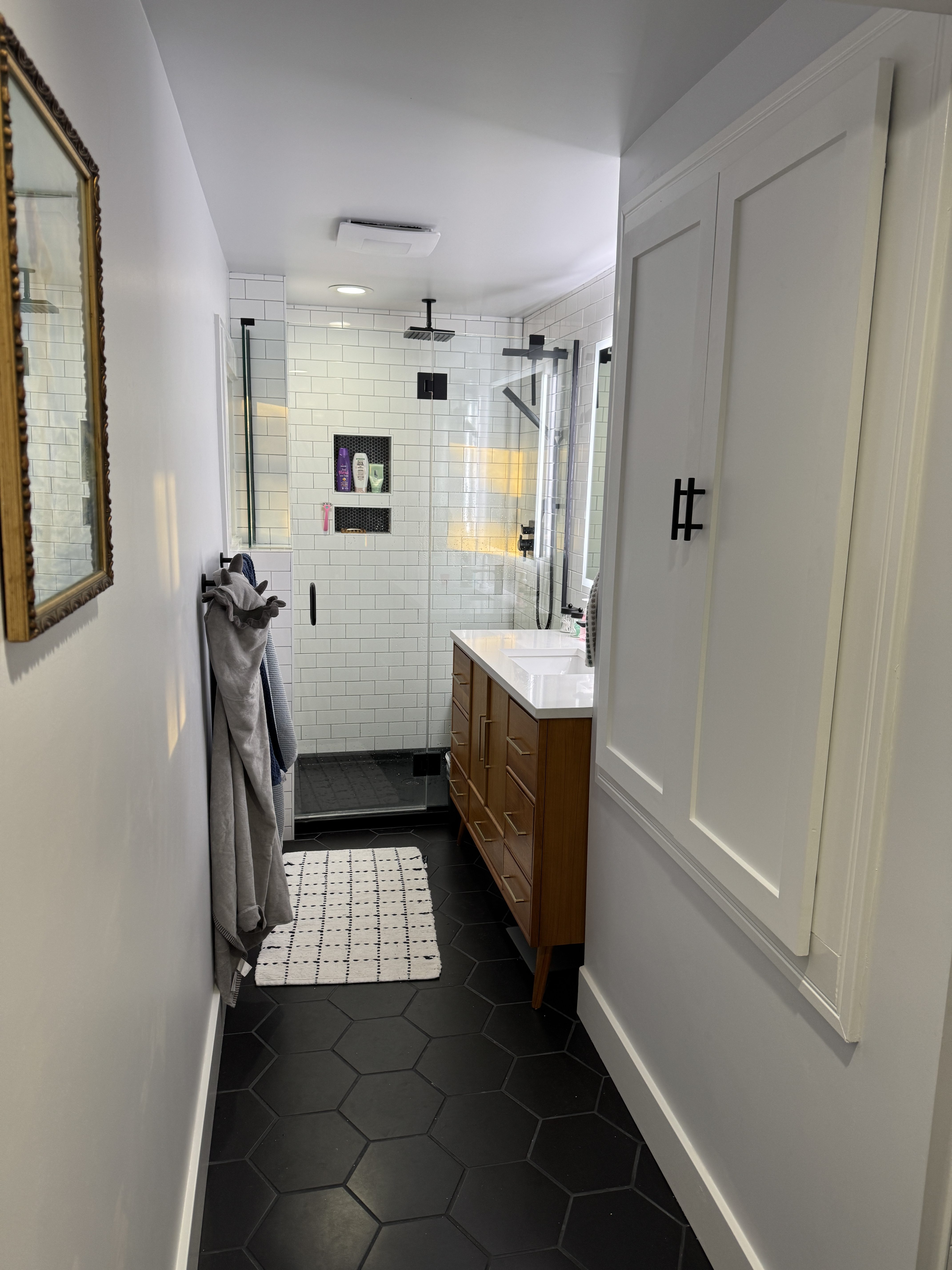Master bathroom looking toward the walk-in shower, with a walnut vanity and a built-in white linen cabinet