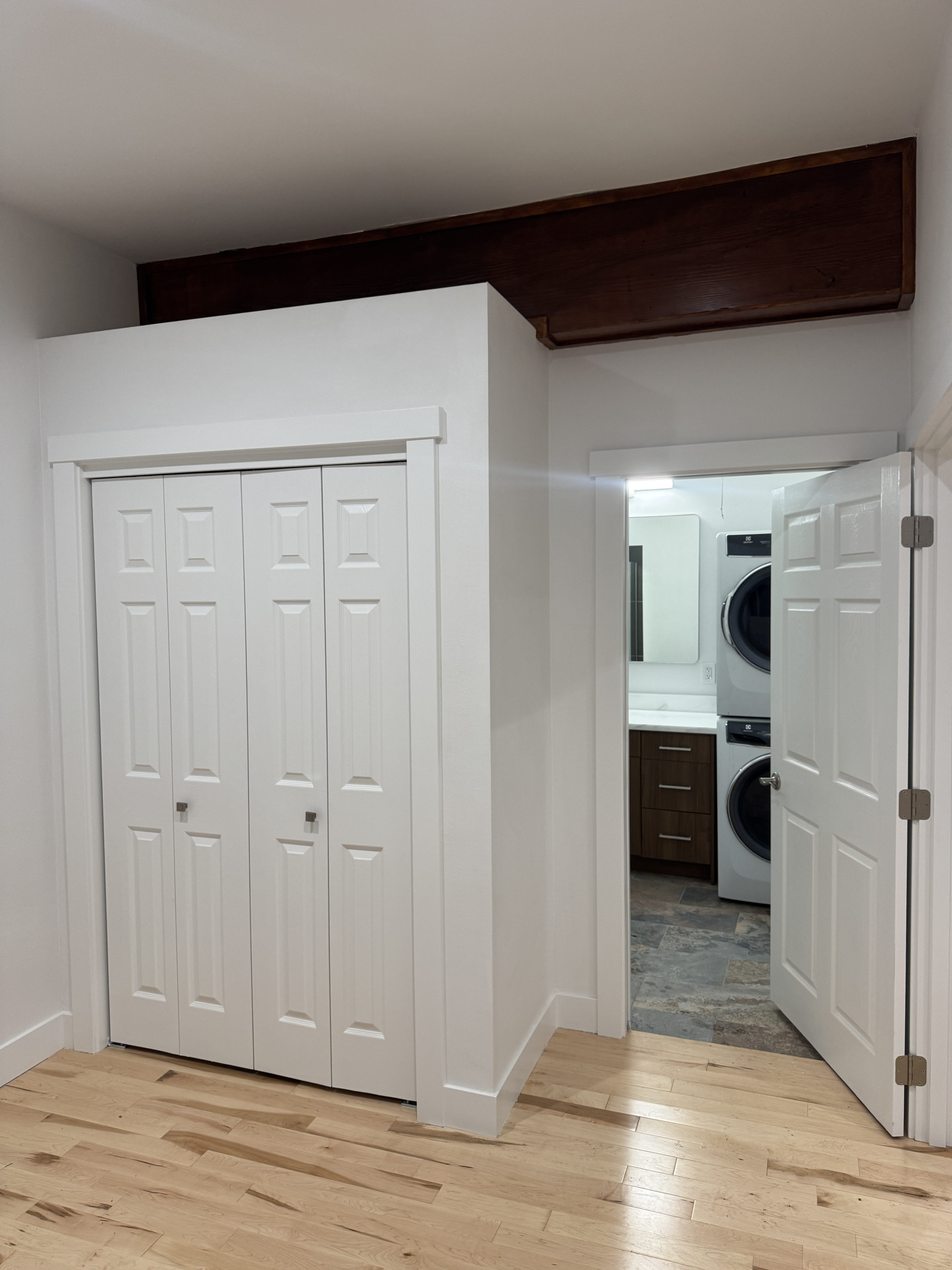 Kenmore ADU kitchen with stone waterfall island, walnut cabinetry, stainless steel range and refrigerator, caged glass pendant lights, and a custom knotty alder entry door with leaded glass sidelights