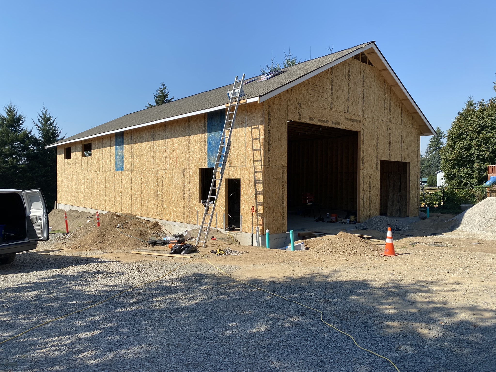 Completed wood-framed commercial shop new construction in Monroe, Washington, with shingled gable roof and oversized elevated overhead door