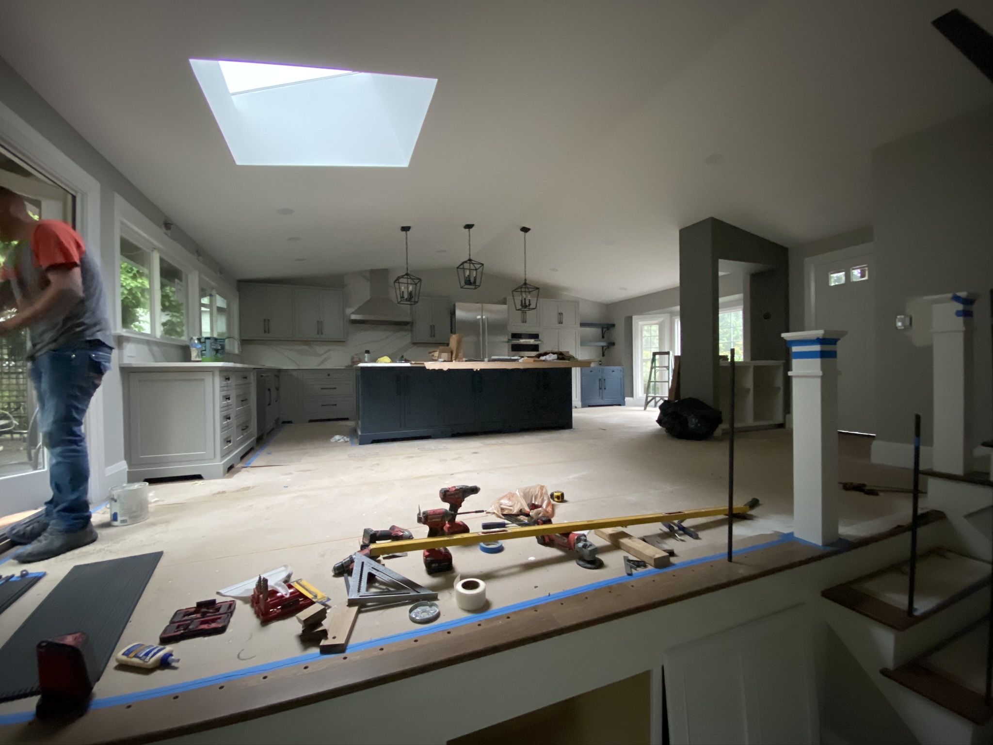 Finished open-concept kitchen with oversized navy island and pendant lighting