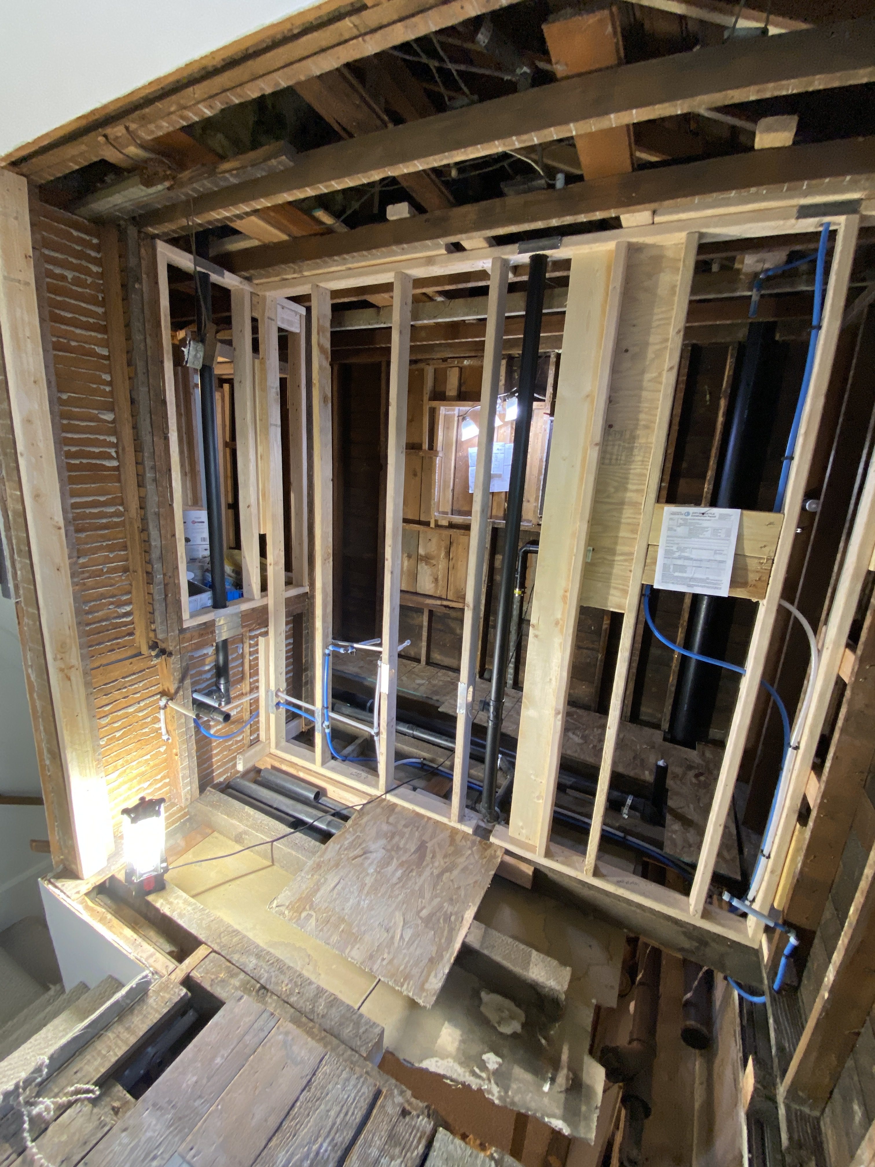 New bathroom framing with rough plumbing, electrical wiring, and a posted City of Bellevue building permit during the remodel