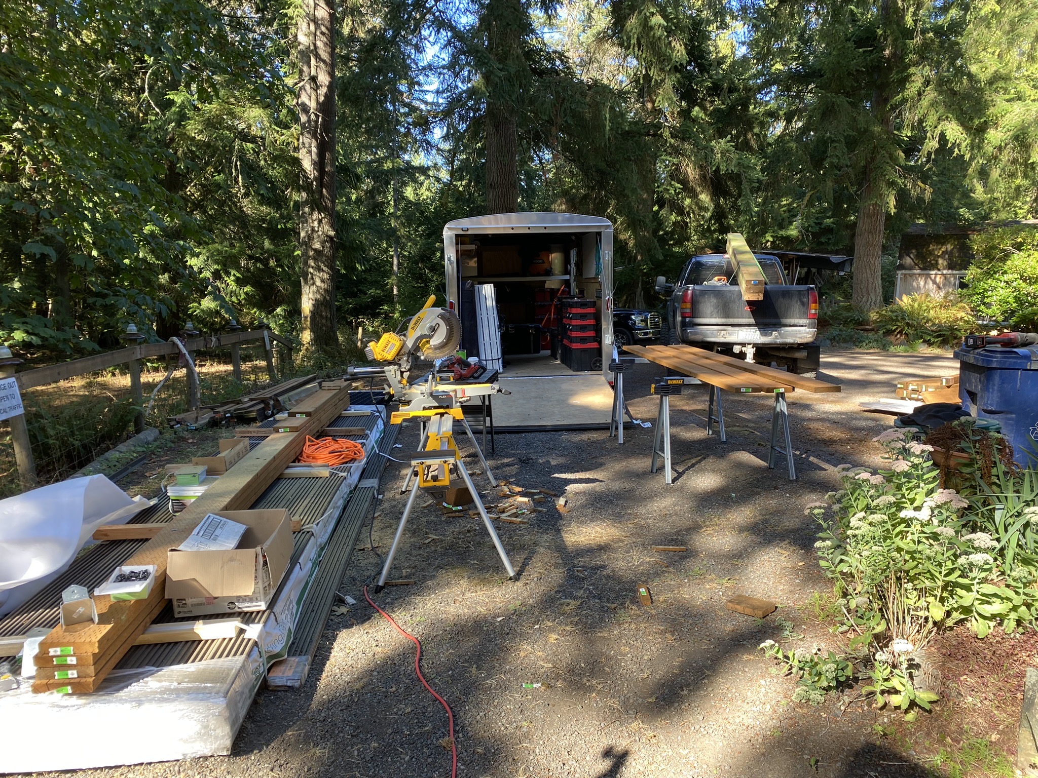 Pelletier Construction jobsite setup in Carnation WA with enclosed tool trailer, miter saw station, and staged composite decking material