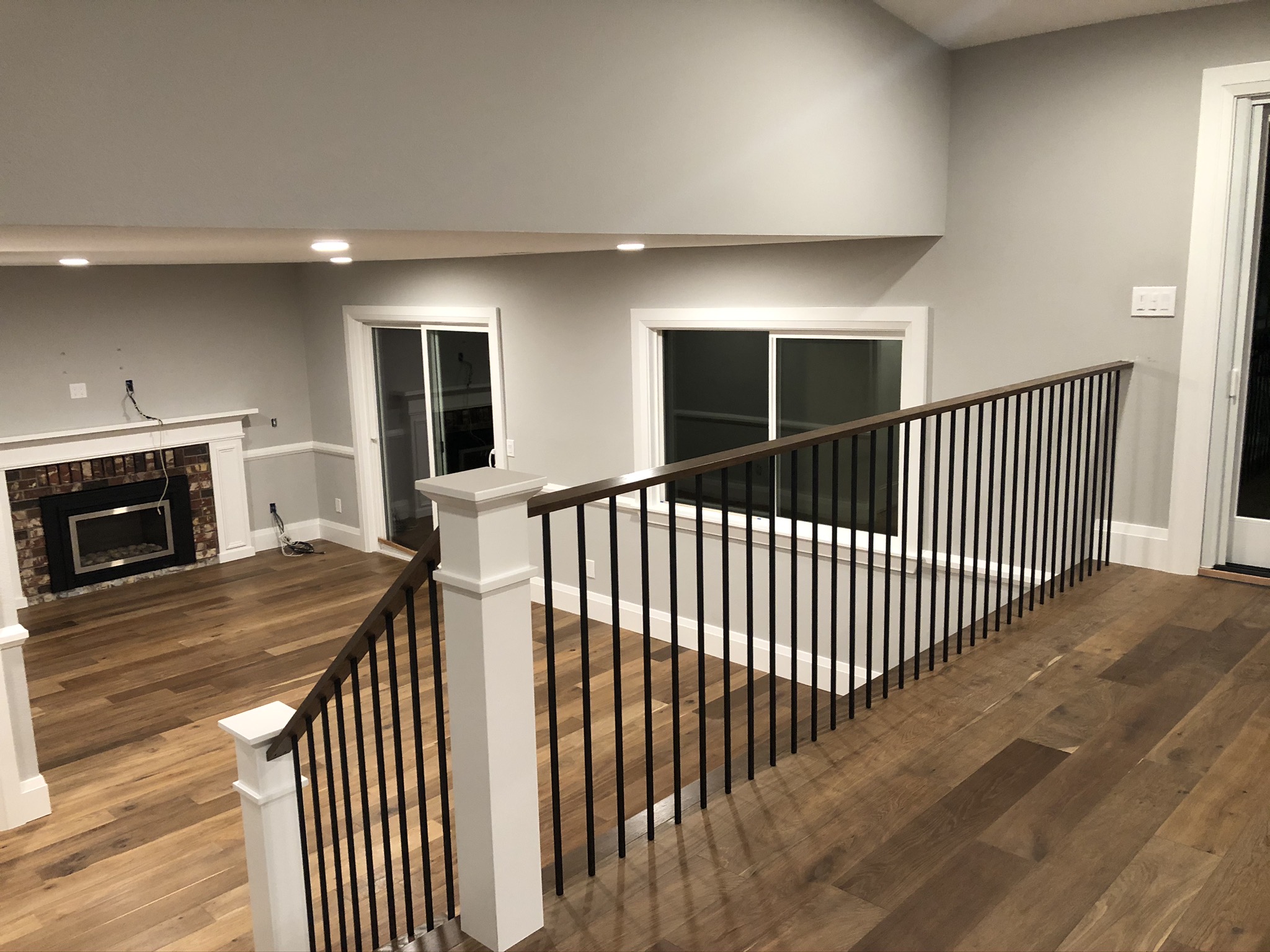 Finished living area with custom railing, fireplace surround and white-oak floors
