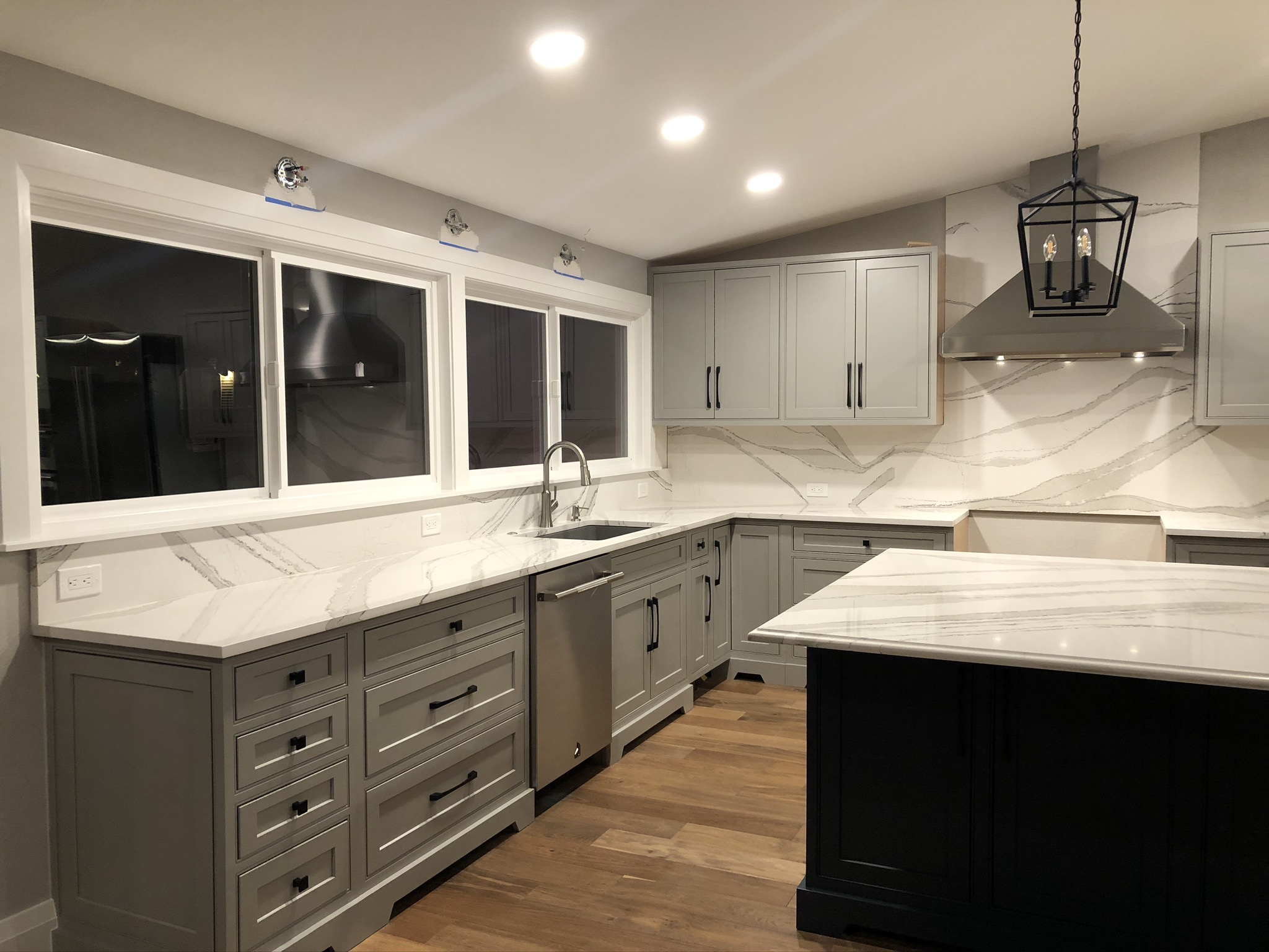Kitchen sink run with full-height countertop-material backsplash