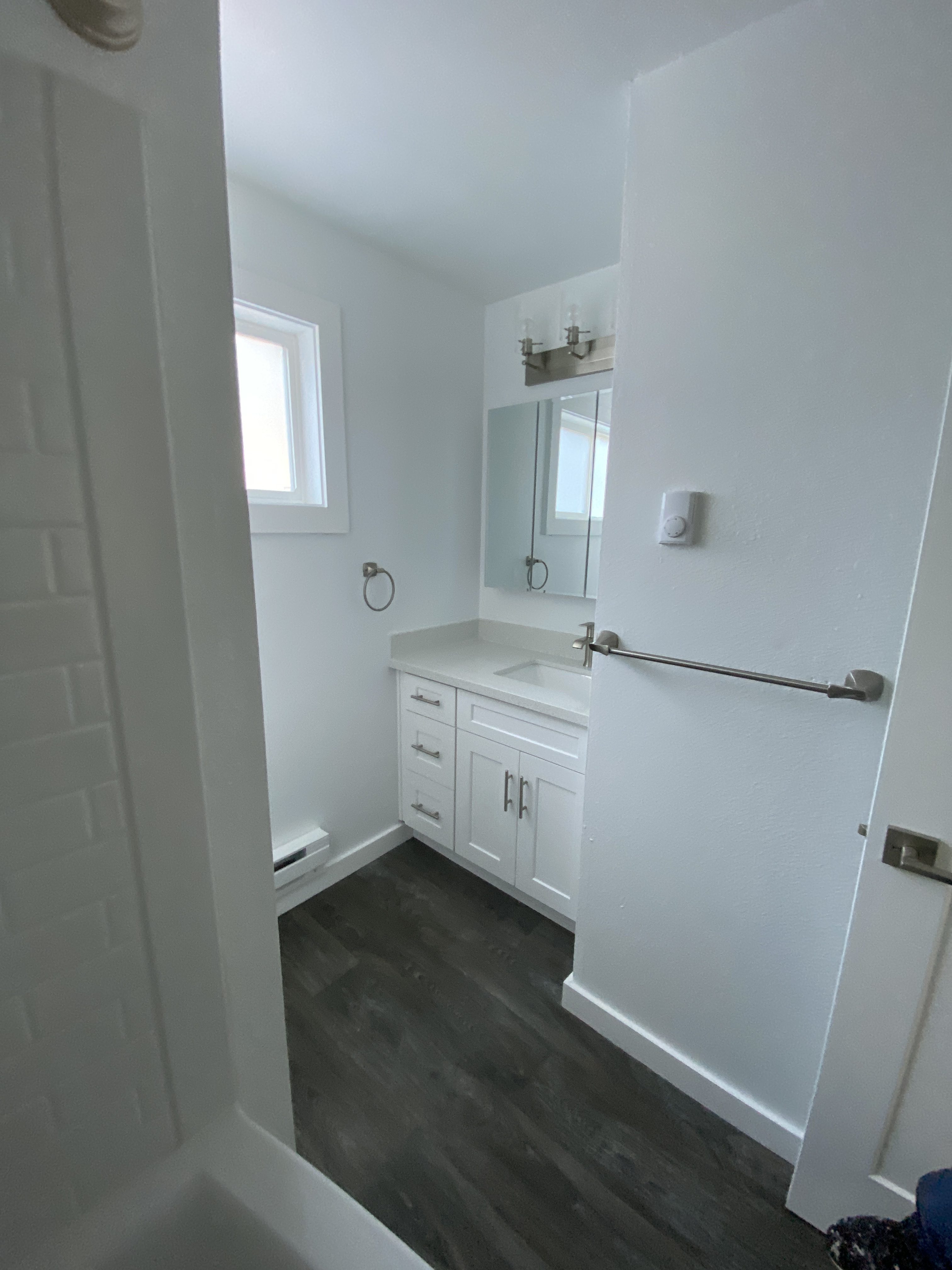 Remodeled apartment kitchen with white shaker cabinets, stainless appliances and wood-look flooring in a Kirkland multiplex