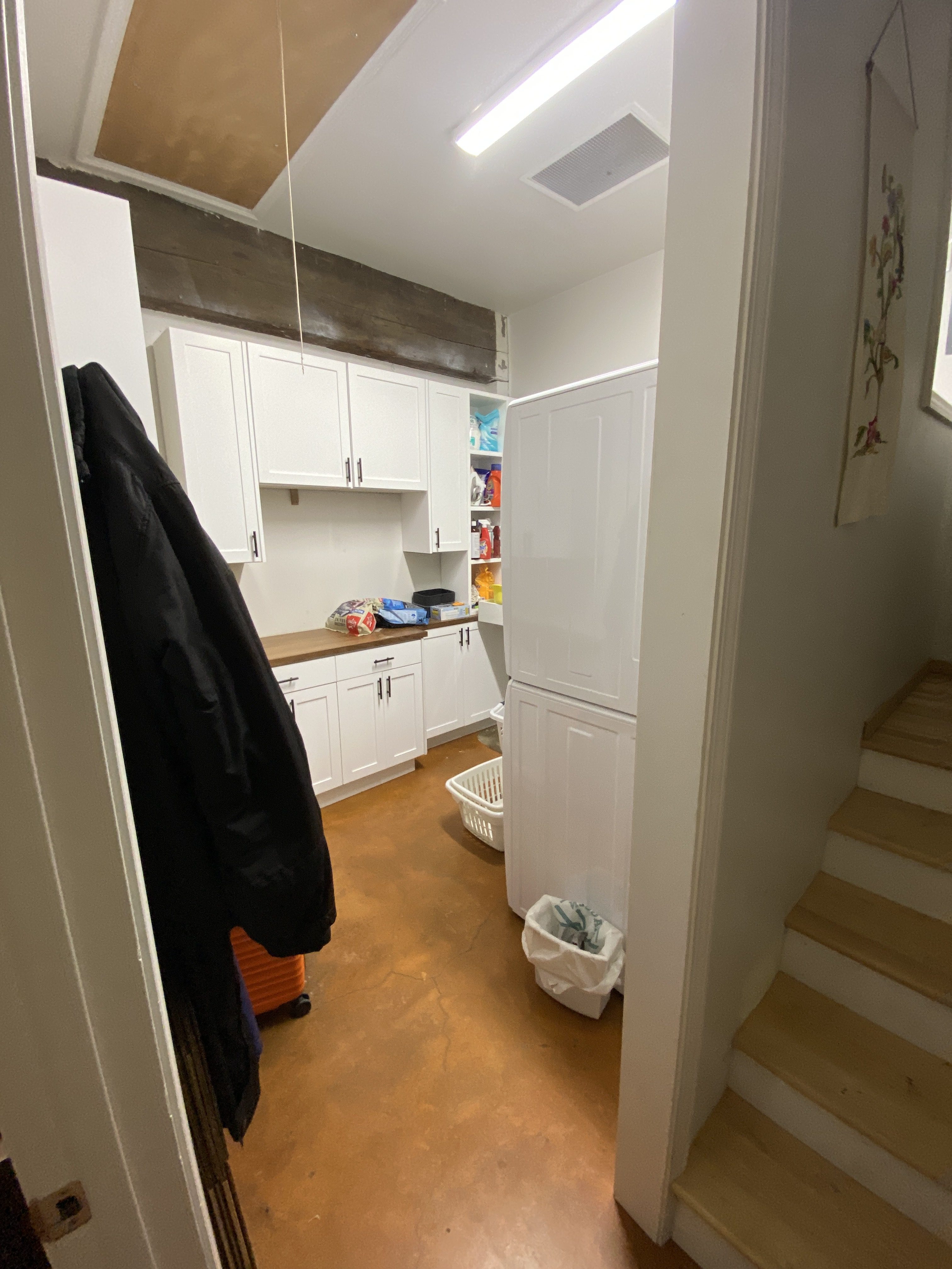 Utility and pantry area in the Kenmore ADU with white shaker cabinetry, butcher-block-style counter, and laundry storage along a hallway
