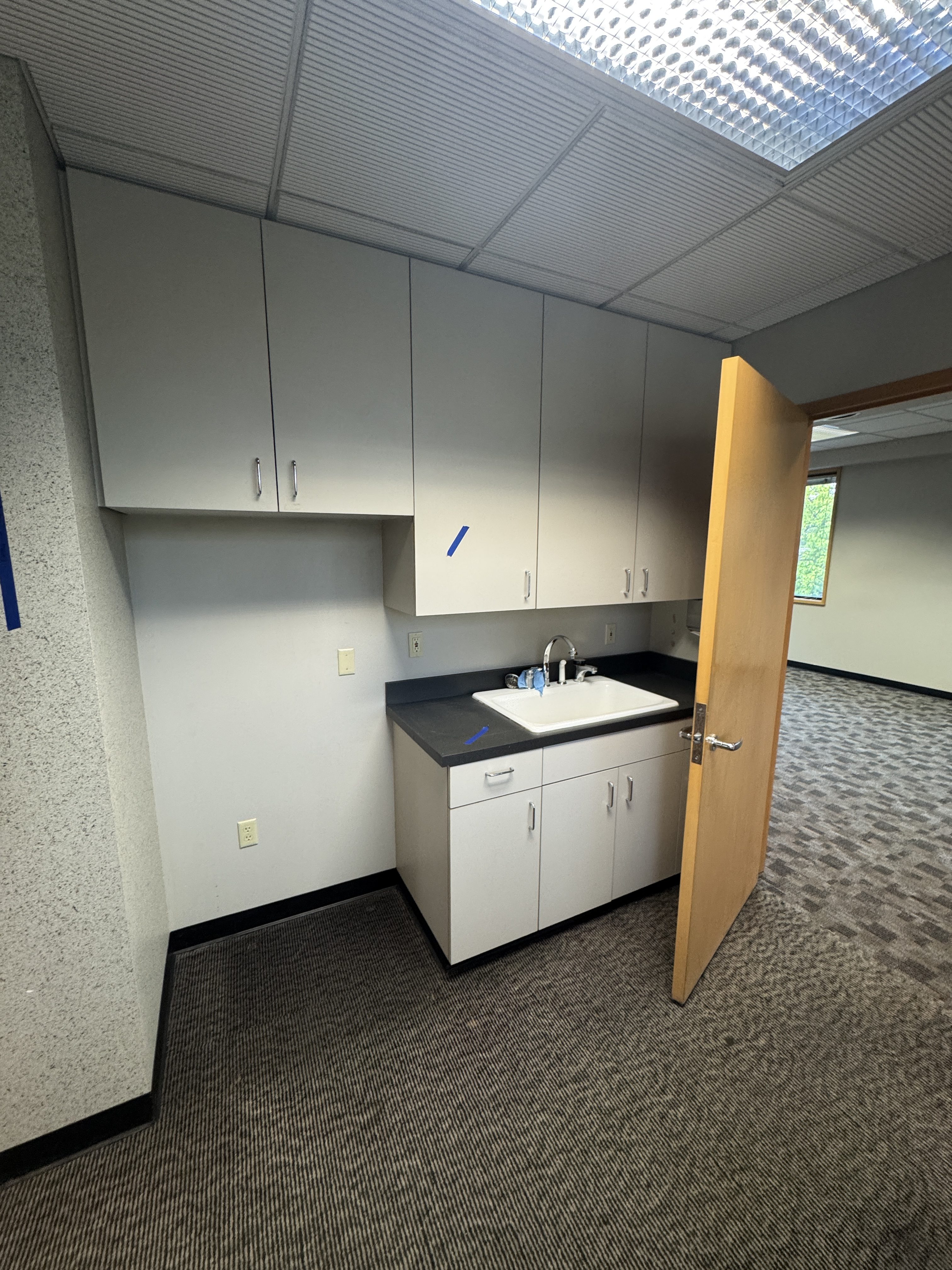 Existing dated kitchen and break area with laminate cabinets before refresh